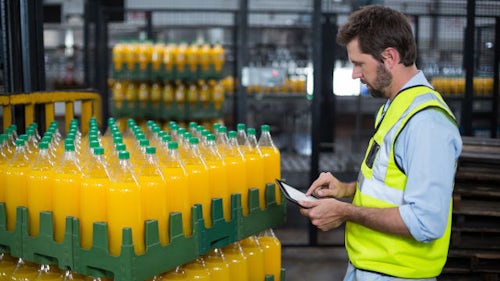 A man checking the palatte of yellow drink bottles.